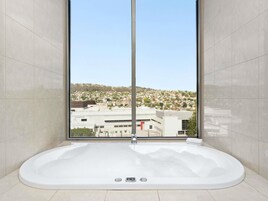 Un baño con una bañera grande, un ventanal con vista a la ciudad y paredes de azulejos.