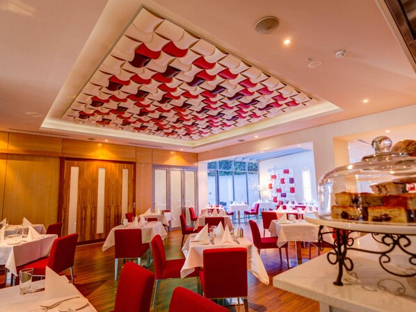 A restaurant with red chairs, white tables, and a ceiling with a geometric pattern. - Mantra Charles Hotel Launceston (Launceston)