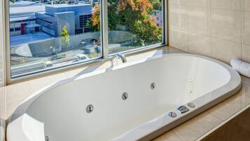 Una bañera grande y moderna con vista a un paisaje urbano a través de un amplio ventanal.