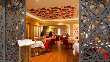 Un restaurante con suelo de madera, sillas rojas y mesas blancas.