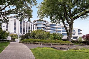 A modern building with a curved facade, surrounded by well-maintained greenery and benches. - Mantra Charles Hotel Launceston (Launceston)