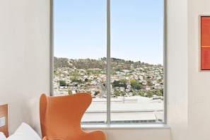 Enjoy a panoramic view of the city from the comfort of this room, featuring a stylish chair and minimalist design.