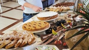 Un bufé con diversas opciones de comida, incluyendo tartas, pastelería y un tazón de parafaits de yogur.