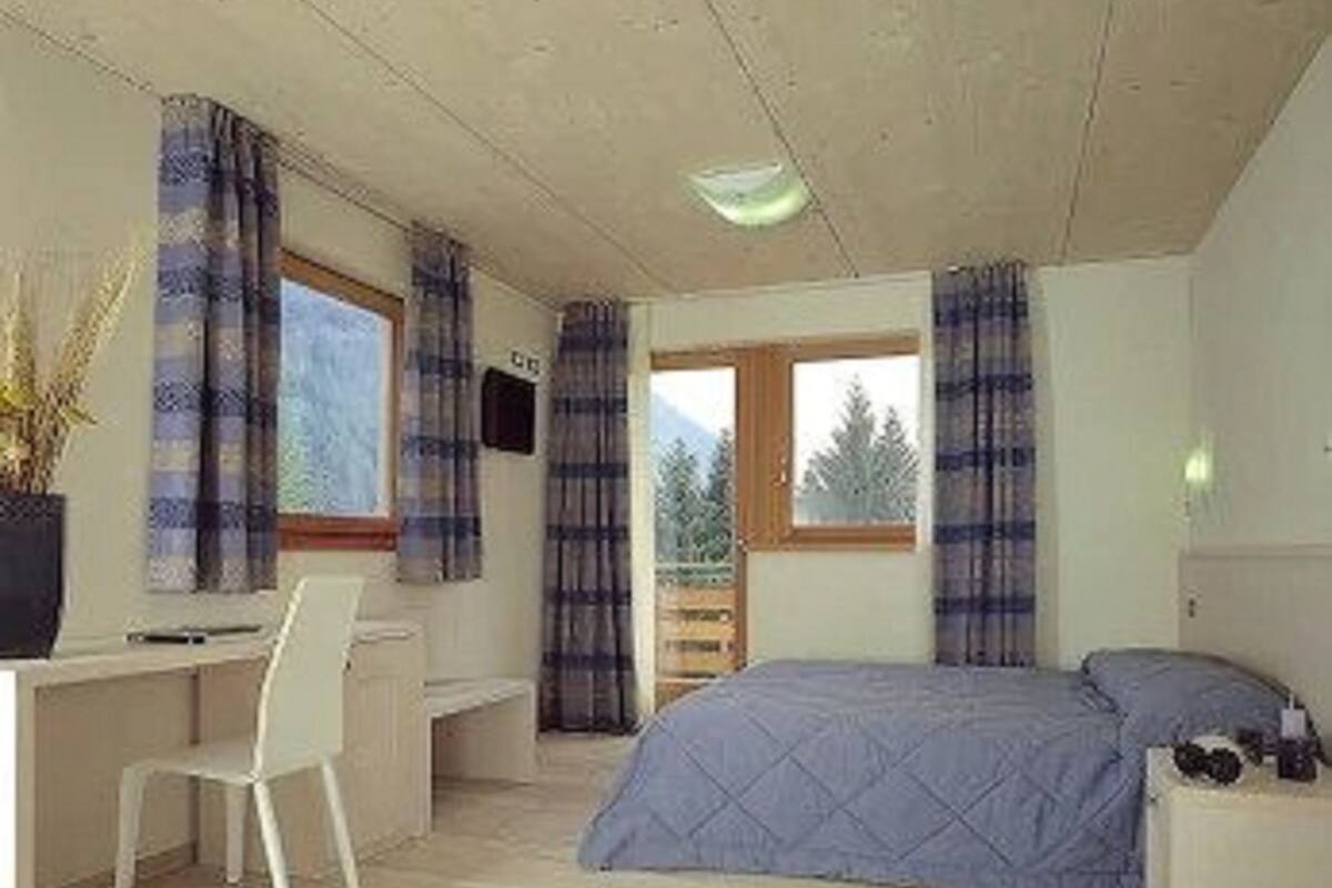 A bedroom with a bed, a desk, and a chair.