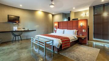 Una habitación de hotel moderna con una cama grande, un escritorio, una silla y un televisor montado en la pared.