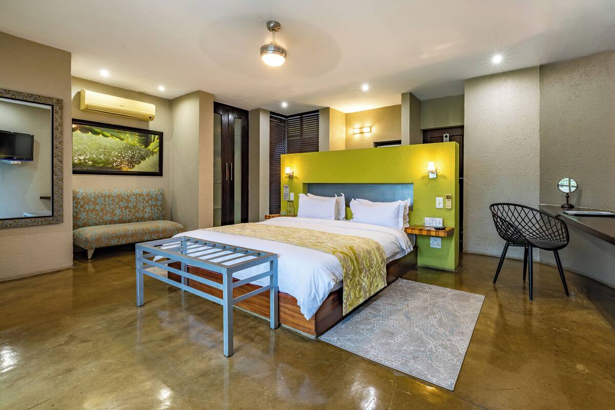 A modern bedroom with a bed, a bench, a desk, and a chair.