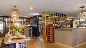 A bar area with a counter, shelves of liquor bottles, and a chandelier. - Francolin Lodge (Mbombela)