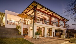 A modern two-story house with a balcony, large windows, and a well-lit entrance. - Francolin Lodge (Mbombela)