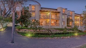 A multi-story hotel with balconies, a landscaped garden, and a paved walkway. - Francolin Lodge (Mbombela)