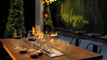 A wooden table with two glasses of red wine, a candle holder, and a menu stand.