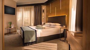 Una habitación de hotel moderna con una cama grande, mesitas de noche, un televisor y vistas a la ciudad.