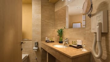 A modern bathroom with a marble sink, a mirror, a potted plant, and a handheld showerhead.