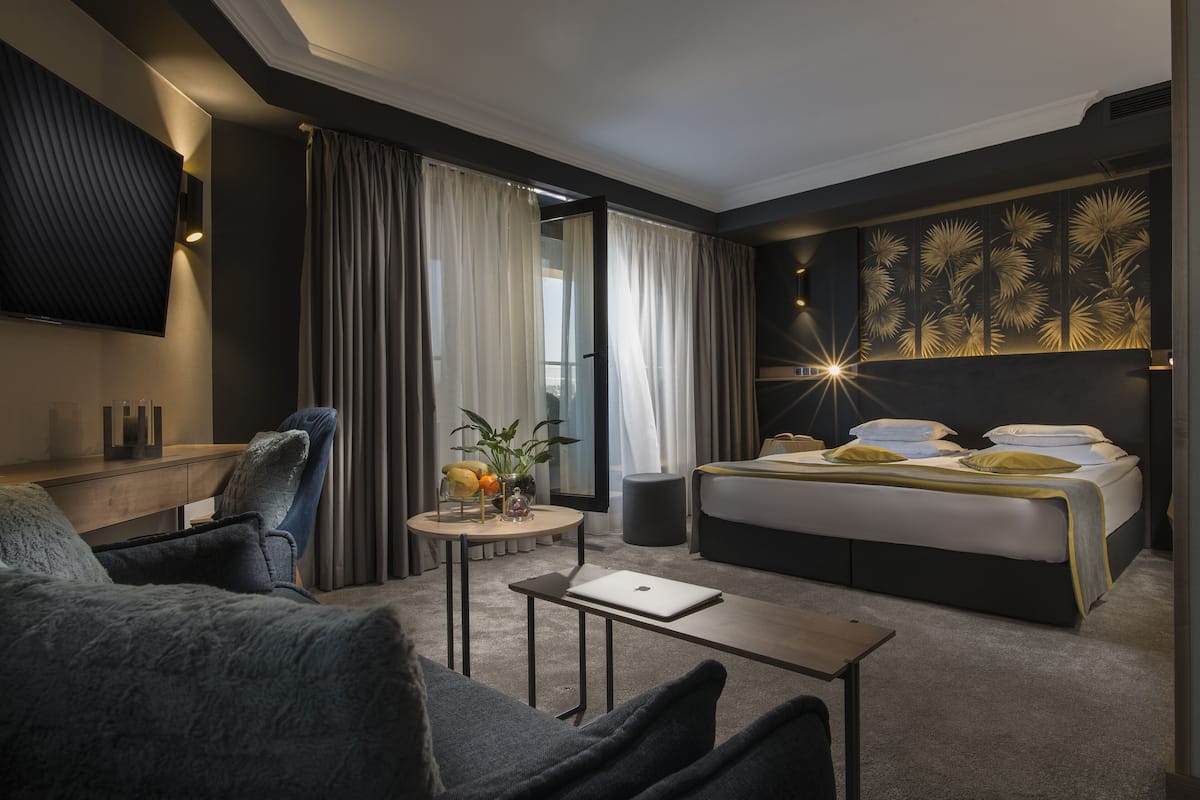 A modern hotel room with a bed, a desk, a chair, and a small table.