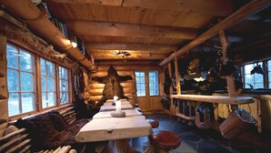 A rustic cabin interior with a long wooden table, benches, and a stone floor. - Engholm Husky Design Lodge (Karasjok)