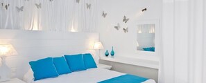 A modern bedroom with a white bed, blue pillows, and a nightstand with two lamps.