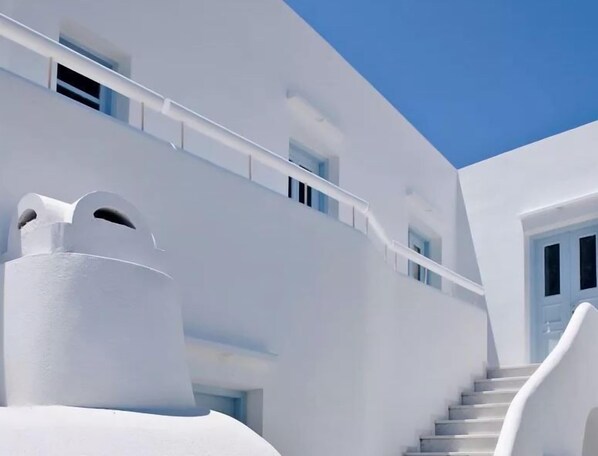 A white building with a curved staircase and a balcony.