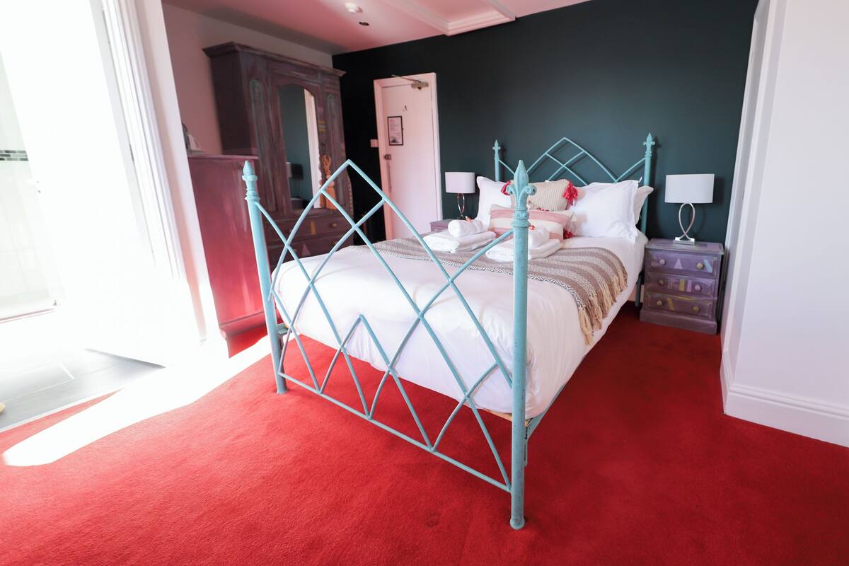 A bedroom with a bed, a nightstand, a dresser, and a door.