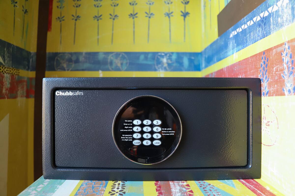A black Chubb safes with a keypad, set against a colorful wall with geometric patterns.