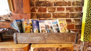 A wooden box filled with various travel brochures against a brick wall. - The Cavalaire (Brighton)