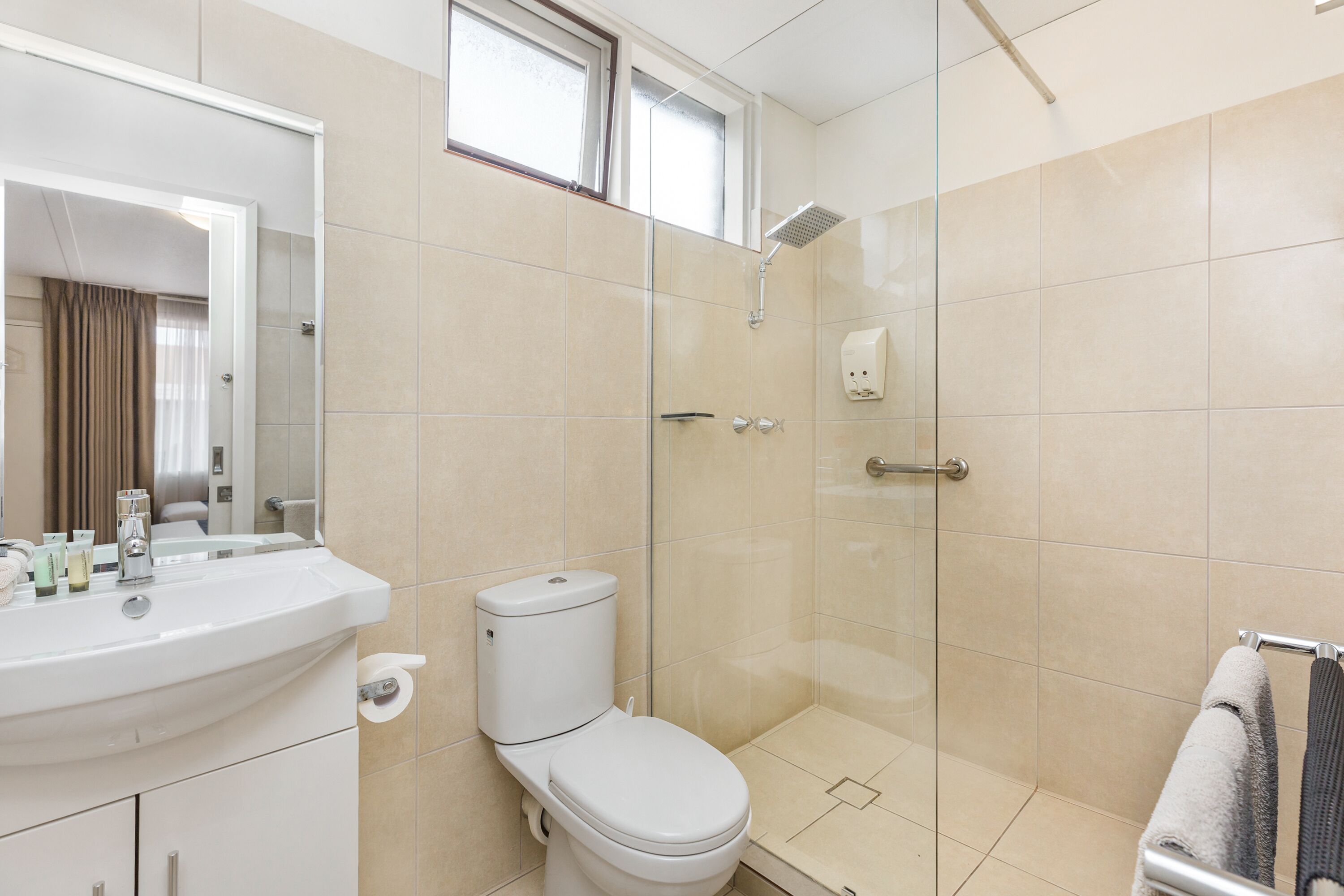 Un baño moderno con lavabo blanco, inodoro y ducha con mampara de vidrio.