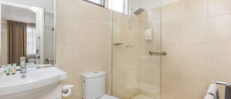 A modern bathroom with a white sink, toilet, and glass-enclosed shower.