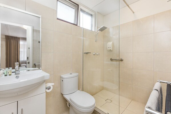 Une salle de bain moderne avec un lavabo blanc, des toilettes et une douche à parois de verre.