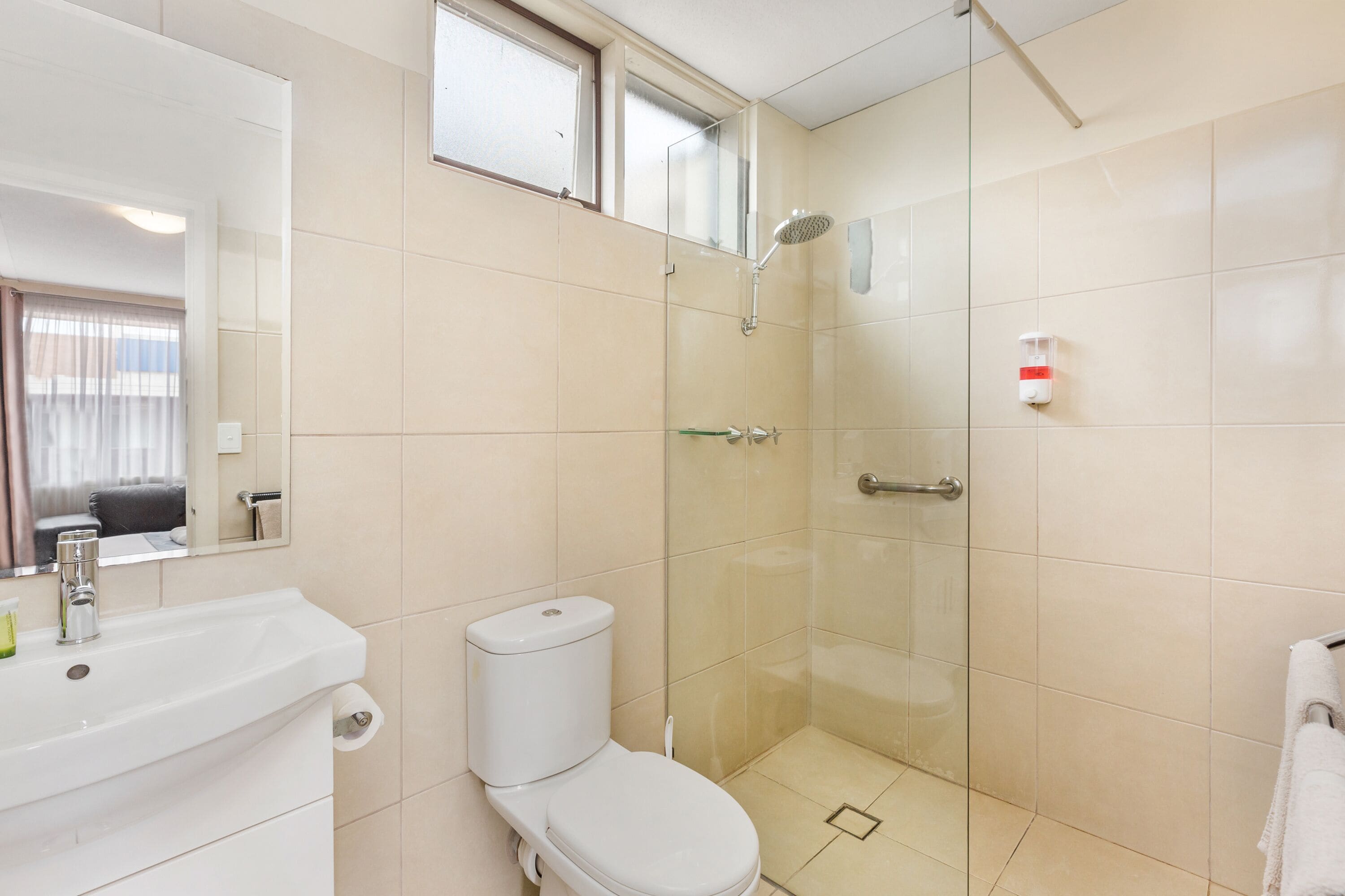 A bathroom with a toilet, sink, and glass-enclosed shower.