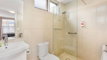 A bathroom with a toilet, sink, and glass-enclosed shower.