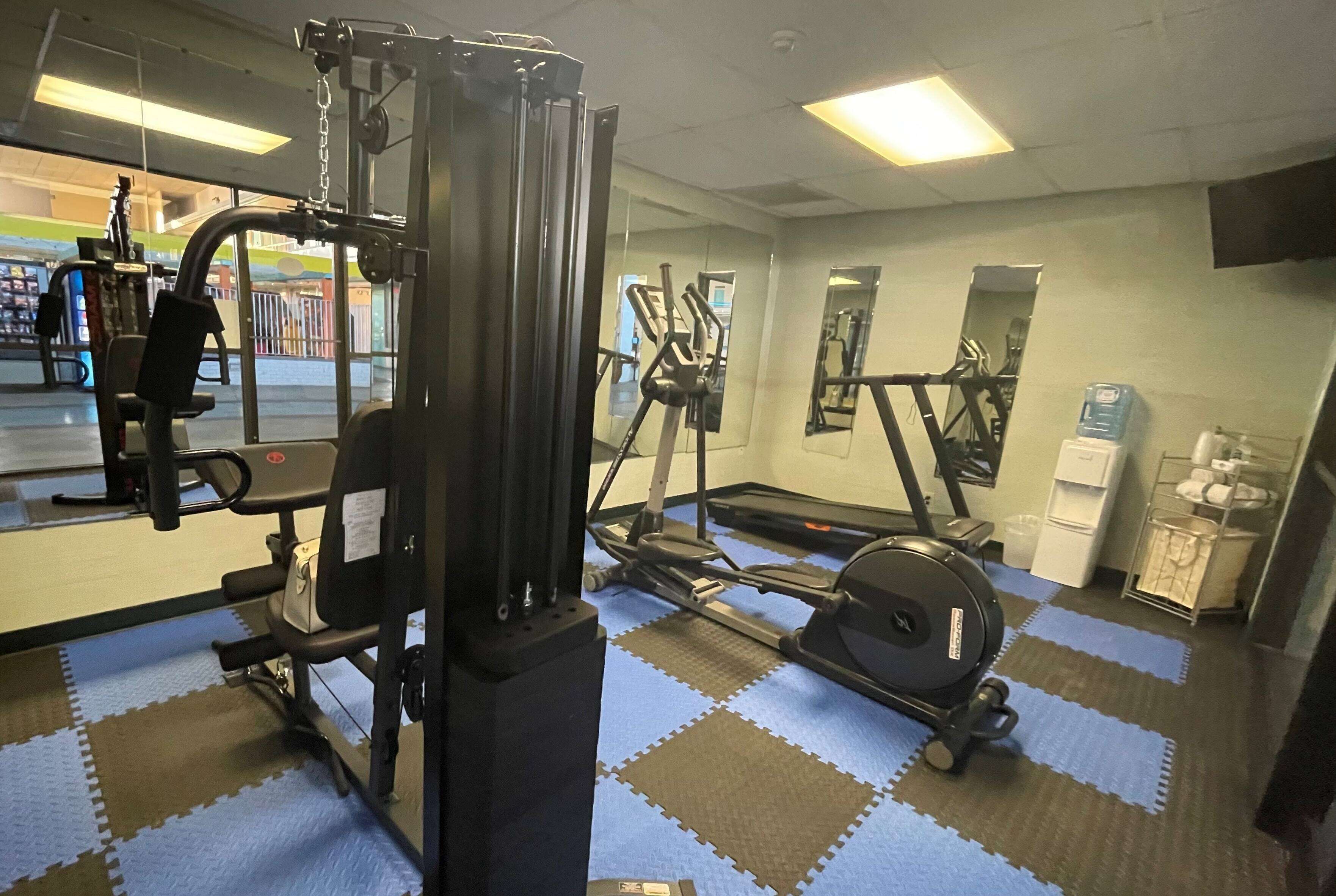 Un gimnasio con equipo de ejercicio, dispensador de agua y un espejo.