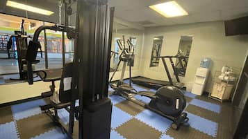 A gym with exercise equipment, a water dispenser, and a mirror.