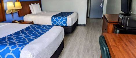 A hotel room with two beds, a desk, a television, and a door.