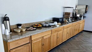 A kitchen with a granite countertop, wooden cabinets, and a herringbone-patterned floor. - Baymont by Wyndham Hannibal (Hannibal)