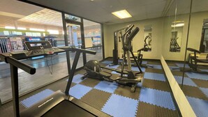 A gym with cardio equipment, mirrored walls, and a view of a Pepsi store outside. - Baymont by Wyndham Hannibal (Hannibal)