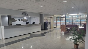A clean, modern reception area with a reception desk, a clock, and a potted plant. - Baymont by Wyndham Hannibal (Hannibal)