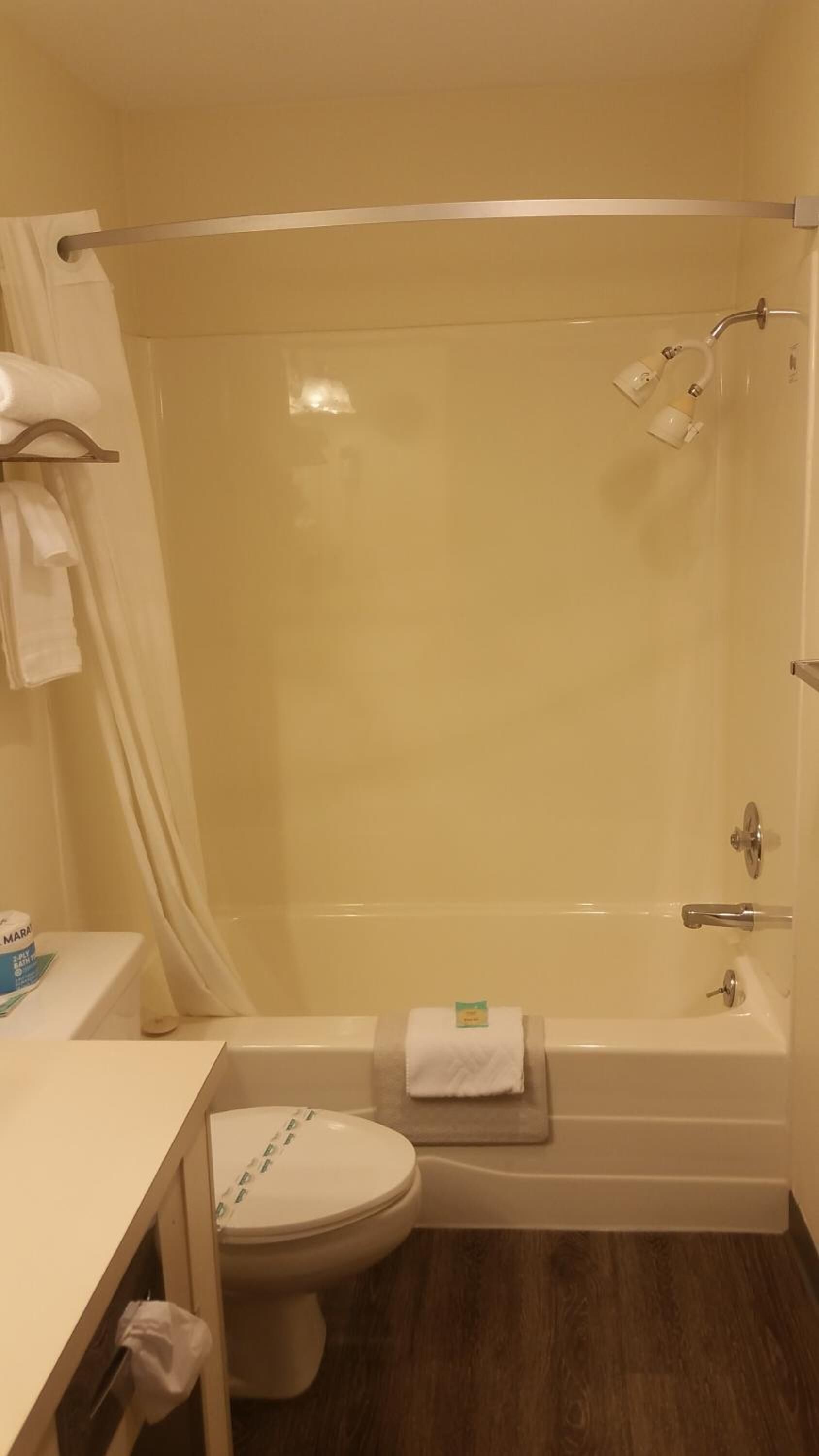 Un baño con ducha de vidrio, inodoro y lavamanos con toallero.