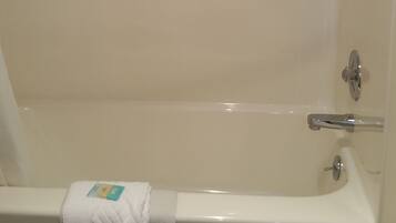 A bathtub with a towel and a shower head.