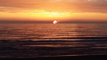 A sunset over a calm sea with gentle waves.