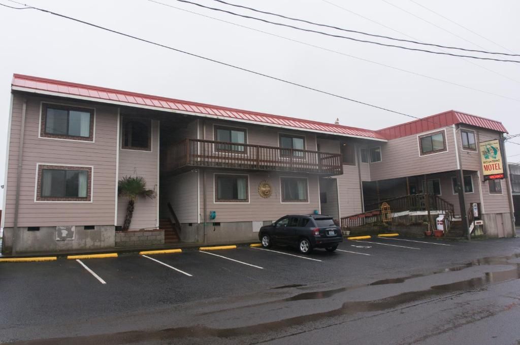 A motel with a red roof, a balcony, and a parking lot.