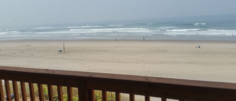 A beach with a wooden railing, a sandy shore, and the ocean in the background.