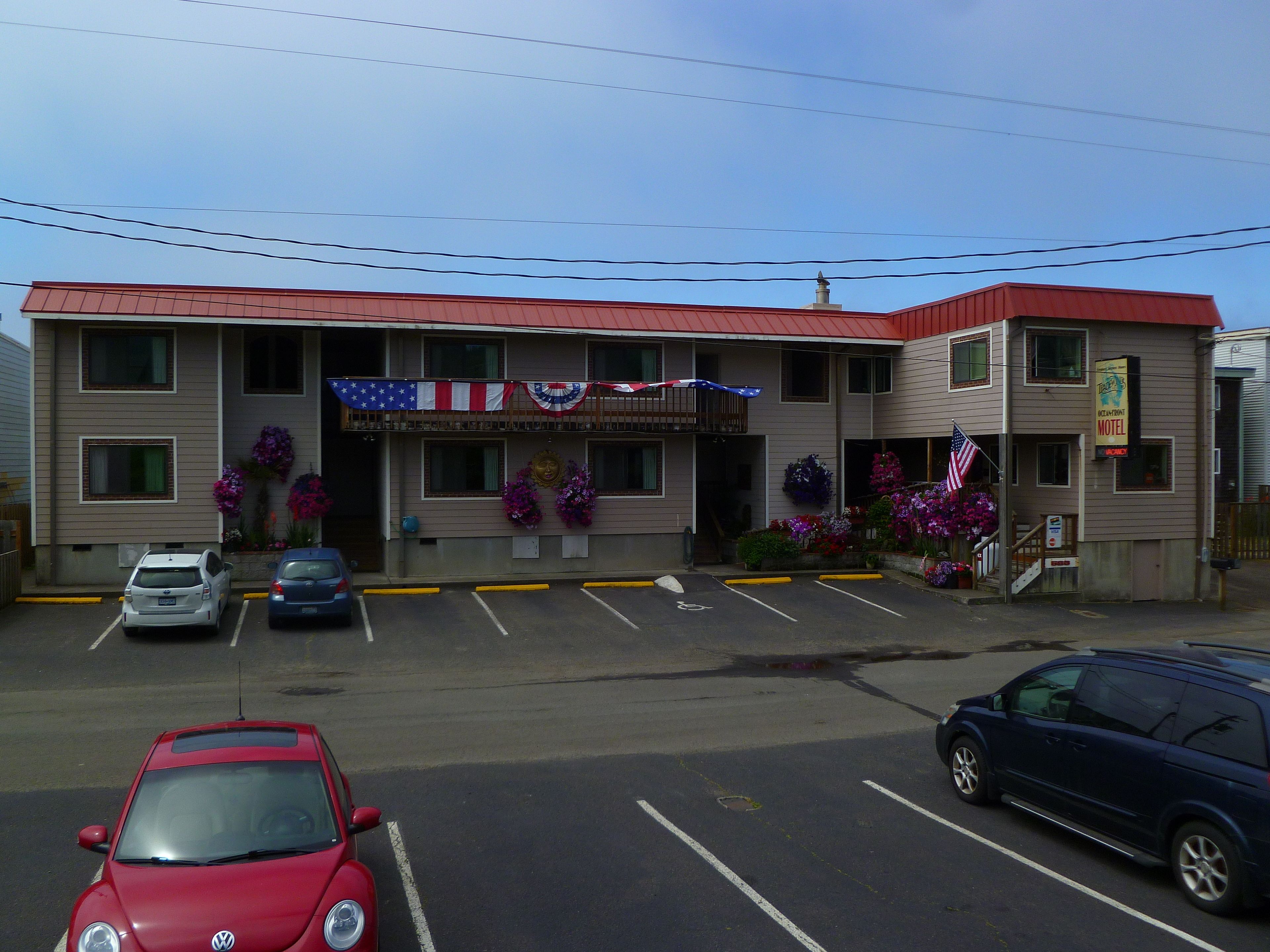 A motel with a red roof, American flag decorations, and a sign indicating it is an Ocean Breeze Motel.