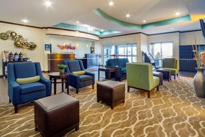 A lobby with seating areas, a reception desk, and a large window providing a view of the city.