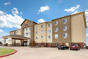 A hotel with a covered entrance, multiple floors, and a parking lot.