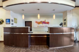 A reception area with a wooden reception desk, a cityscape artwork, and a sign indicating a check-in counter.
