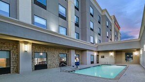 Un hôtel doté d’une piscine, d’une façade en pierre et de nombreuses fenêtres.