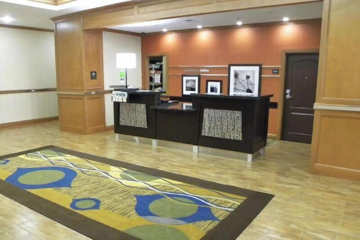 A reception area with a reception desk, framed pictures on the wall, and a patterned carpet.