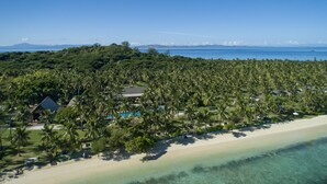 Vue aérienne d’un complexe hôtelier avec une plage, des palmiers et une piscine.