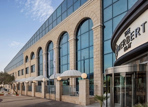 Un bâtiment moderne doté de grandes fenêtres et d’une enseigne indiquant : « The Herbert Hotel ».