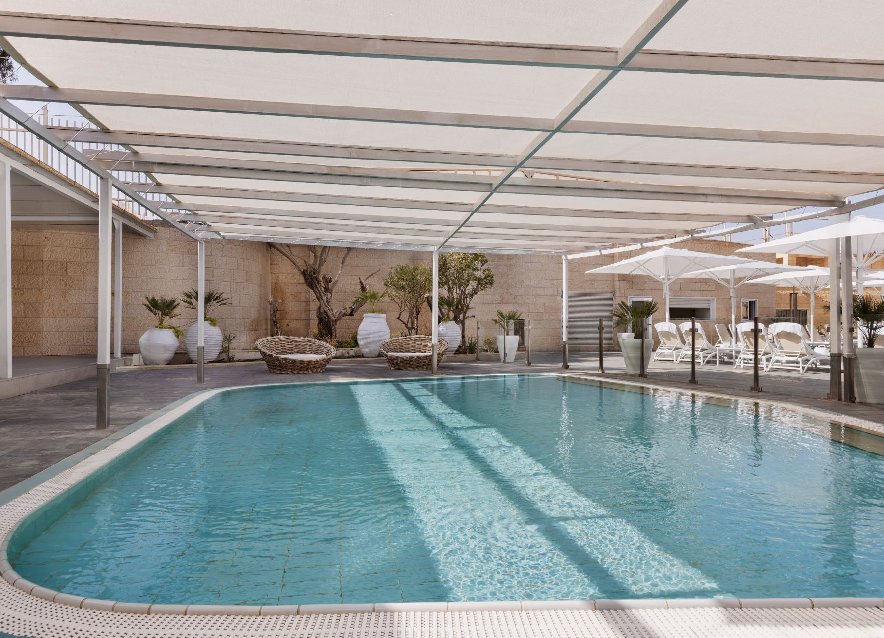 Una piscina amb zona coberta, gandules i plantes en testos.