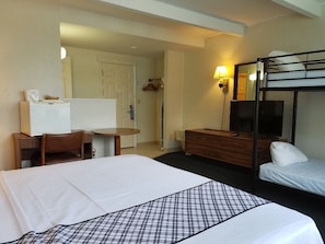 Ein Hotelzimmer mit einem großen Bett, einem Schreibtisch, einem Sessel, einem Schminktisch und einem Schlafsofa.