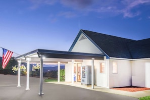 A building with a covered entrance, a flag, and a vending machine. - Lake George, Ny Travelodge (Lake George)